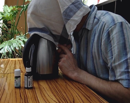 Man inhaling at home hot vapor from a kettle as a remedy for chest infection