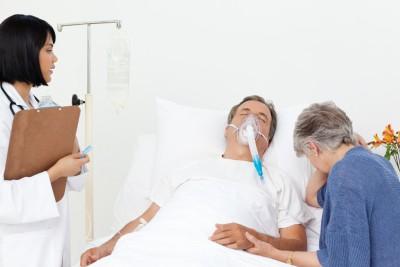 Man on artifical respiration in hospital with wife and nurse